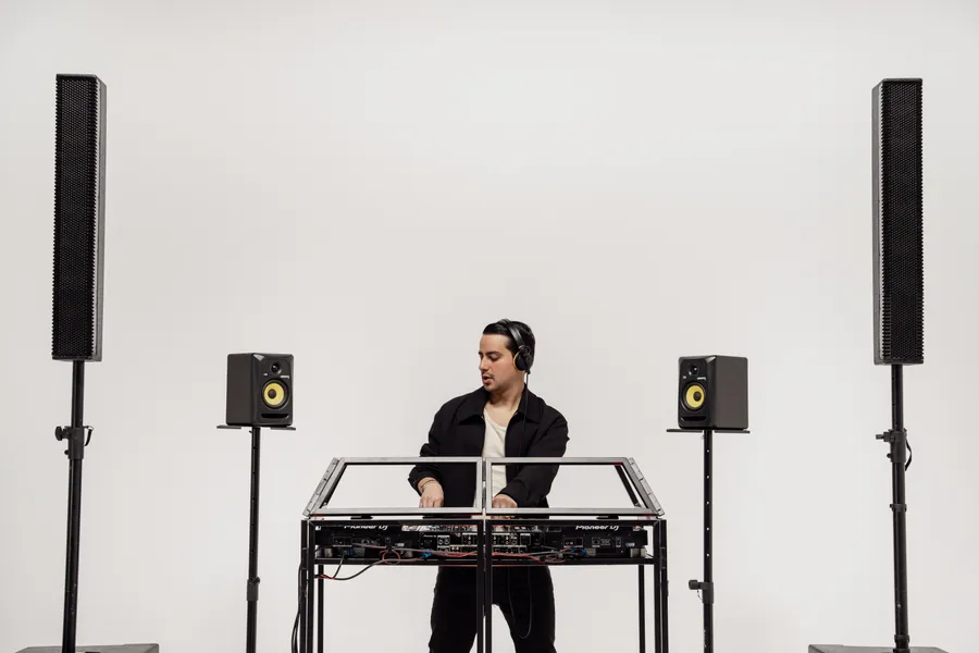 DJ en cabina de estudio entre altavoces Line Array